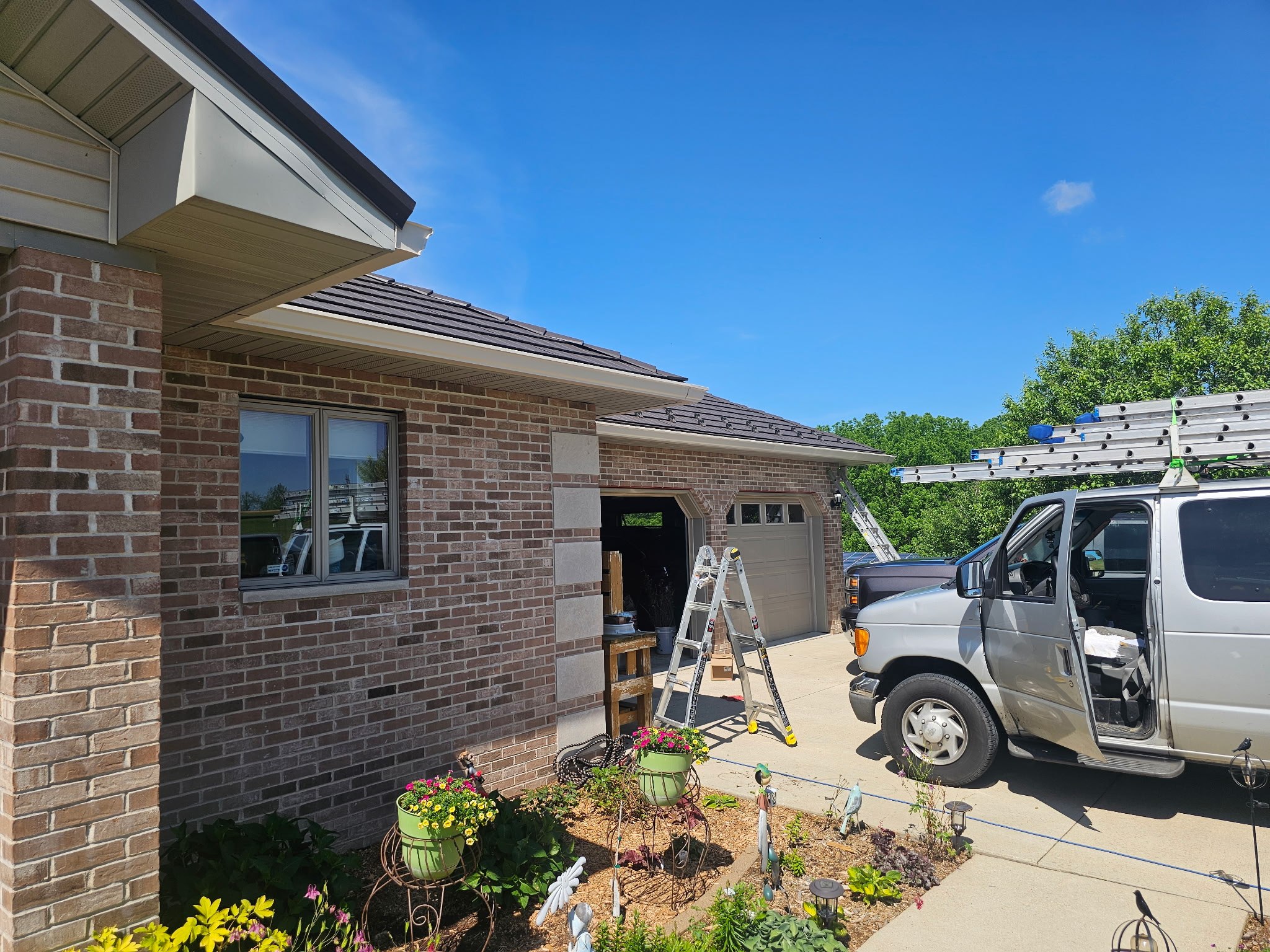 GutterForge gutter guard installation on a brick home with ladders and work van on site